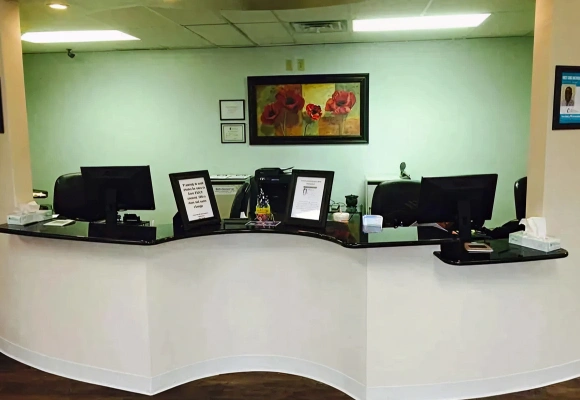 Modern dental office reception desk with computers and green walls