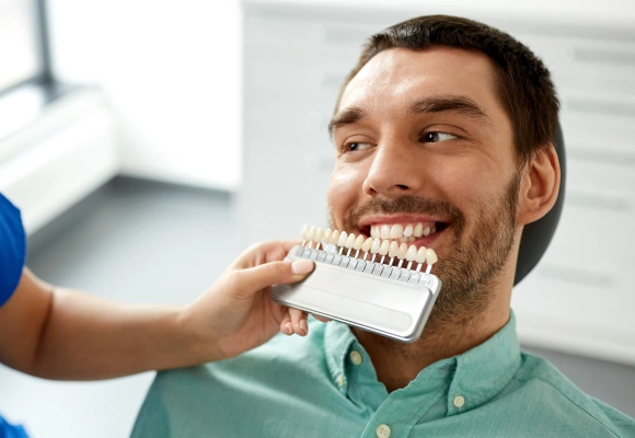 Dentist showing patient dental shade guide for tooth color matching in clinical setting.