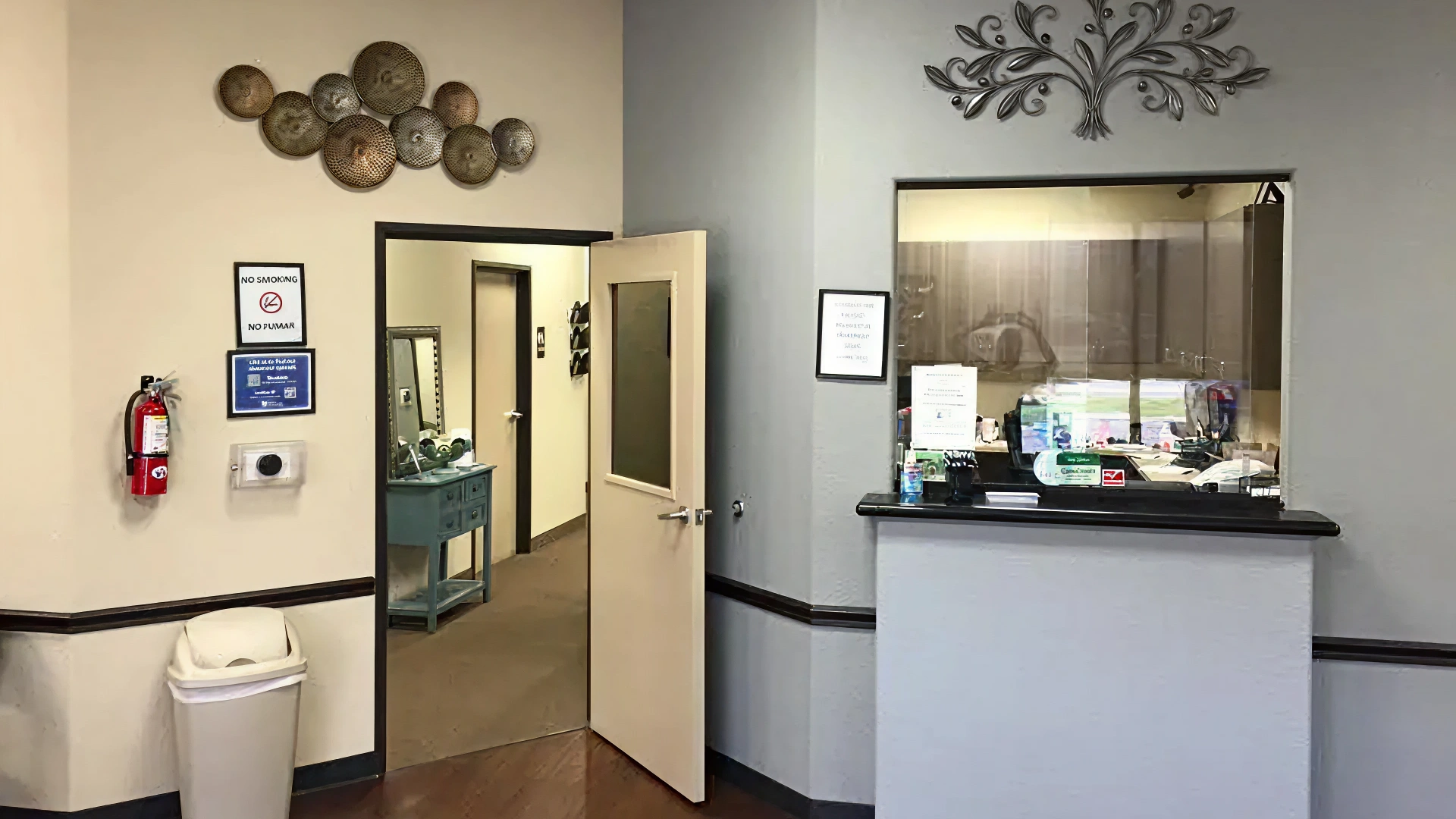 Modern dental office reception area with cream and gray walls, entrance doors, and front desk counter.