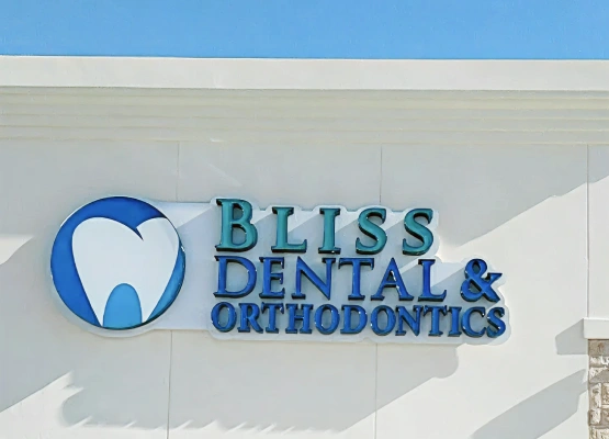 Bliss Dental & Orthodontics logo on white building exterior with blue tooth icon and teal lettering.