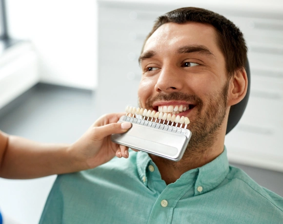 Man holding dental shade guide in dental office setting during teeth color consultation.