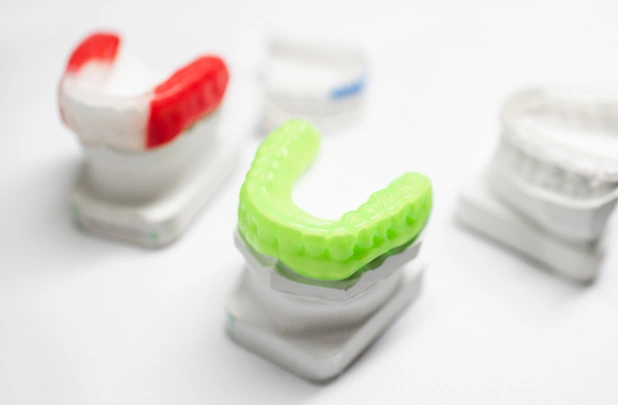 Colorful orthodontic aligners displayed on white stands, showcasing dental treatment options for teeth straightening.