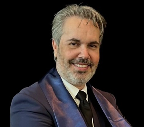 Professional headshot of man in blue blazer and tie against dark background for dental practice.
