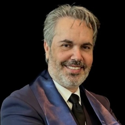 Professional headshot of a man in business attire smiling at camera against dark background.