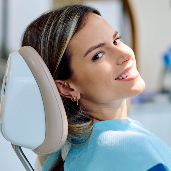 Woman in blue shirt relaxing in dental chair at modern dental office
