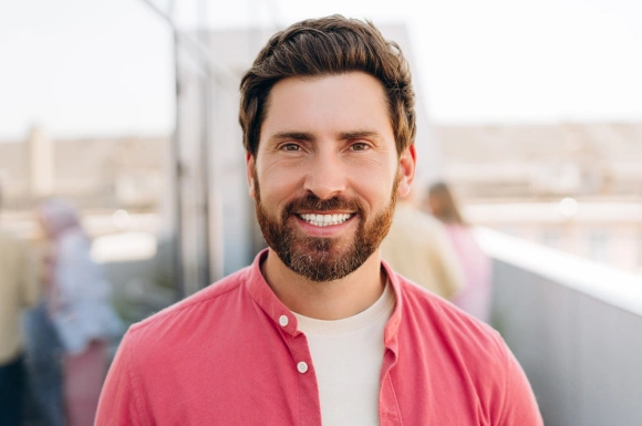 Smiling man in pink shirt on rooftop, dental professional portrait for Bliss Dental & Orthodontics