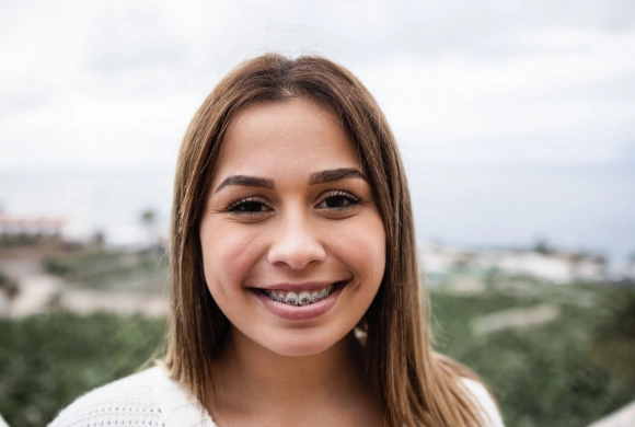 Young woman smiling at camera with green landscape and sky in background