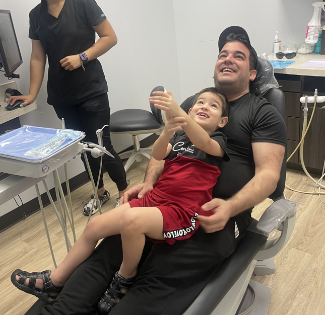 Father and child in dental chair during examination at Bliss Dental & Orthodontics clinic.