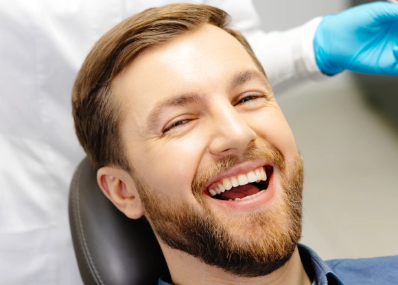 Man smiling in dental chair during professional teeth examination by dentist.